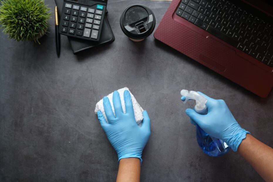 Hände die Schreibtisch reinigen und desinfizieren