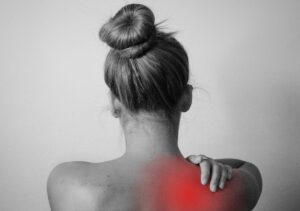 Frau die sich wegen Rückenschmerzen an die Schulter fasst