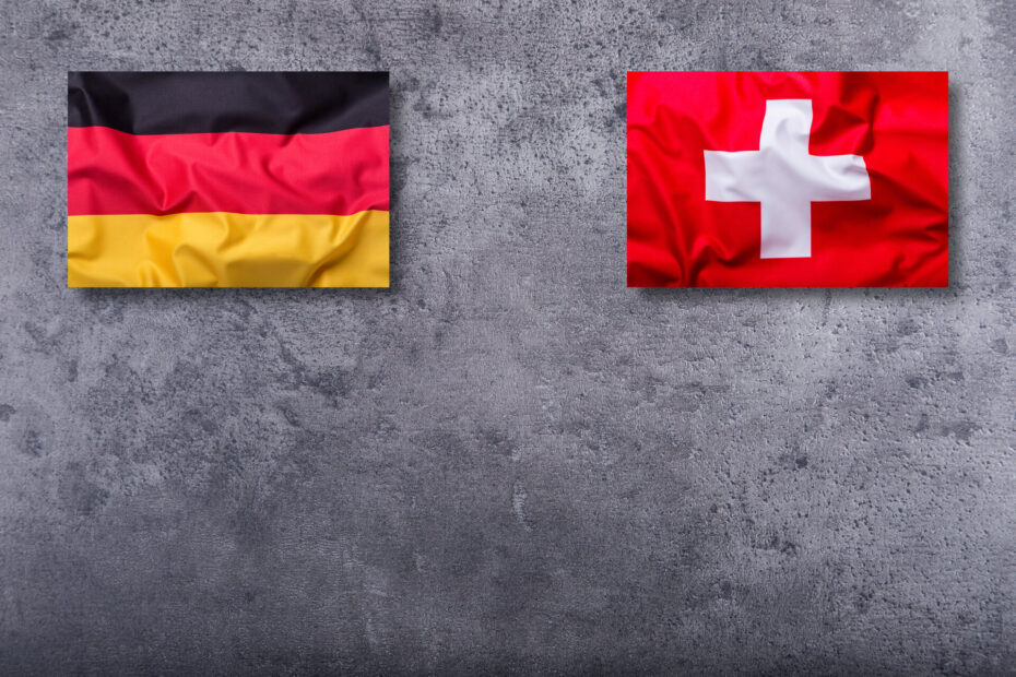 Flaggen Deutschlands und der Schweiz auf Beton-Hintergrund.
