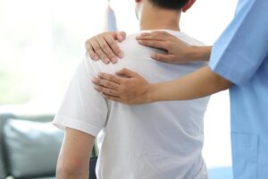 Arzt diagnostiziert Schulterschmerzen eines Mannes im Untersuchungsraum einer Praxis. Chiropraktiker bei Massage und Physiotherapie zur Behandlung der Schulter des Patienten.