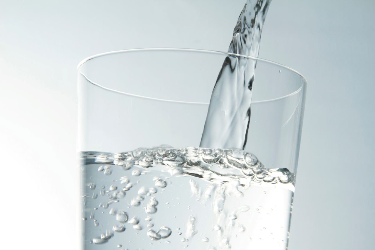 Nahaufnahme von sprudelndem Wasser im Glas das durch eine Entkalkungsanlage gefiltert wurde